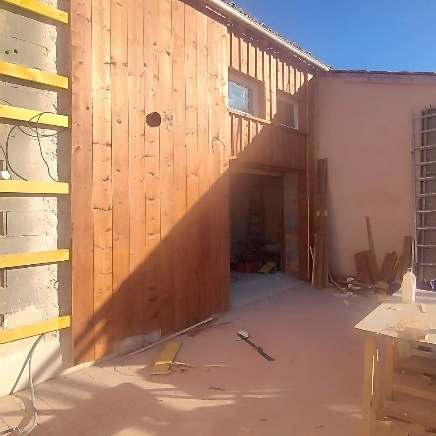 Bardage bois vertical à couvre-joint en cours de finition sur une façade
