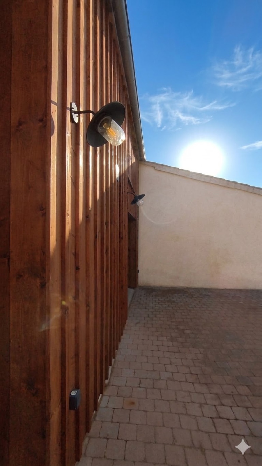 Bardage bois à couvre-joint sur une façade, éclairé par une applique
