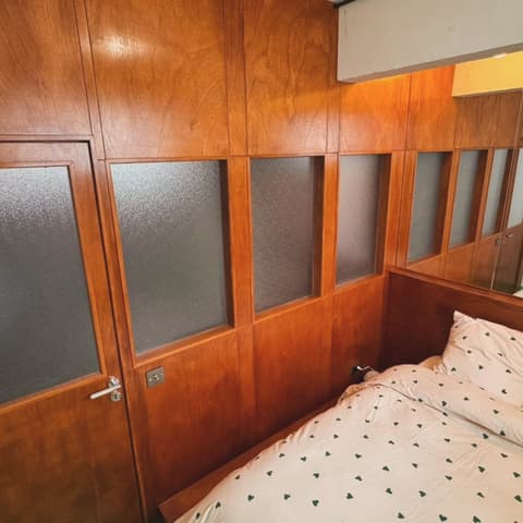 Chambre habillée de boiseries murales en bois verni avec fenêtres intérieures vitrées