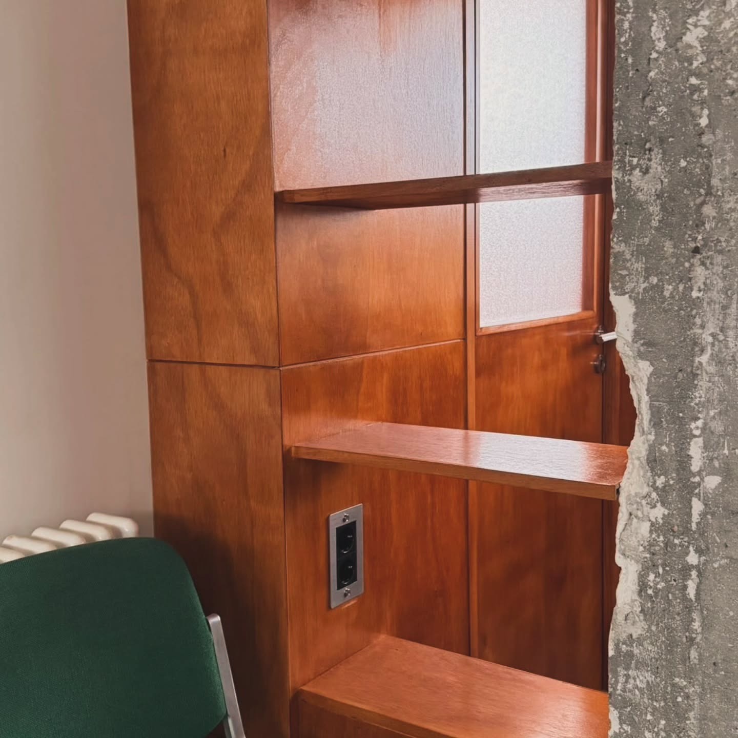 Détail de boiserie murale avec étagère, fenêtre intérieure vitrée et prise intégrée