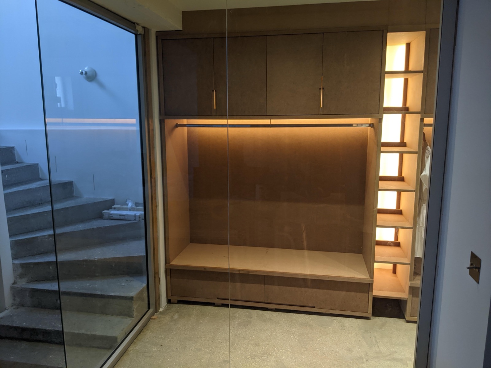 Penderie de dressing sur mesure avec éclairage LED et banc, vue à travers la vitre
