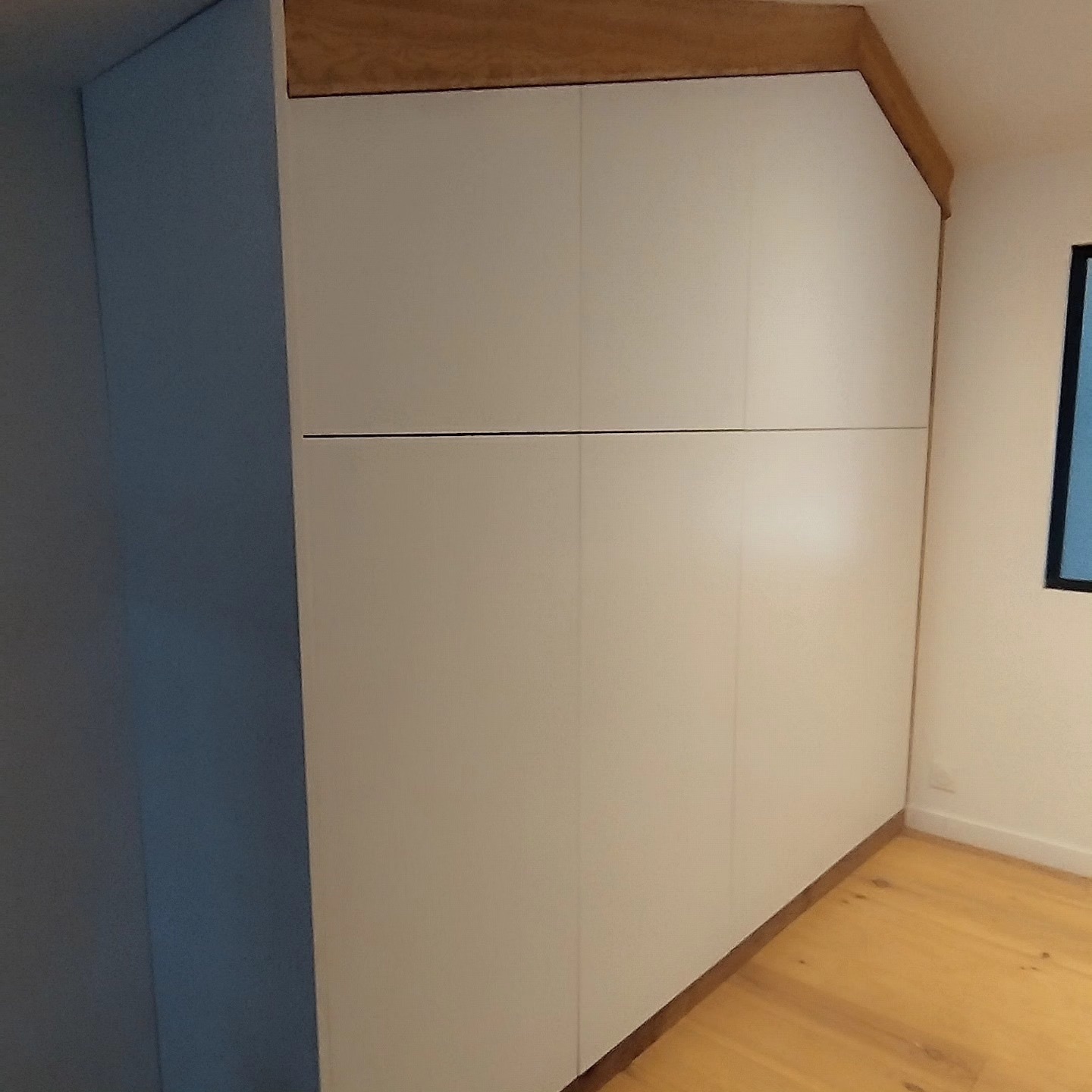 Placard sous combles sur mesure, vue de côté avec mur bleu