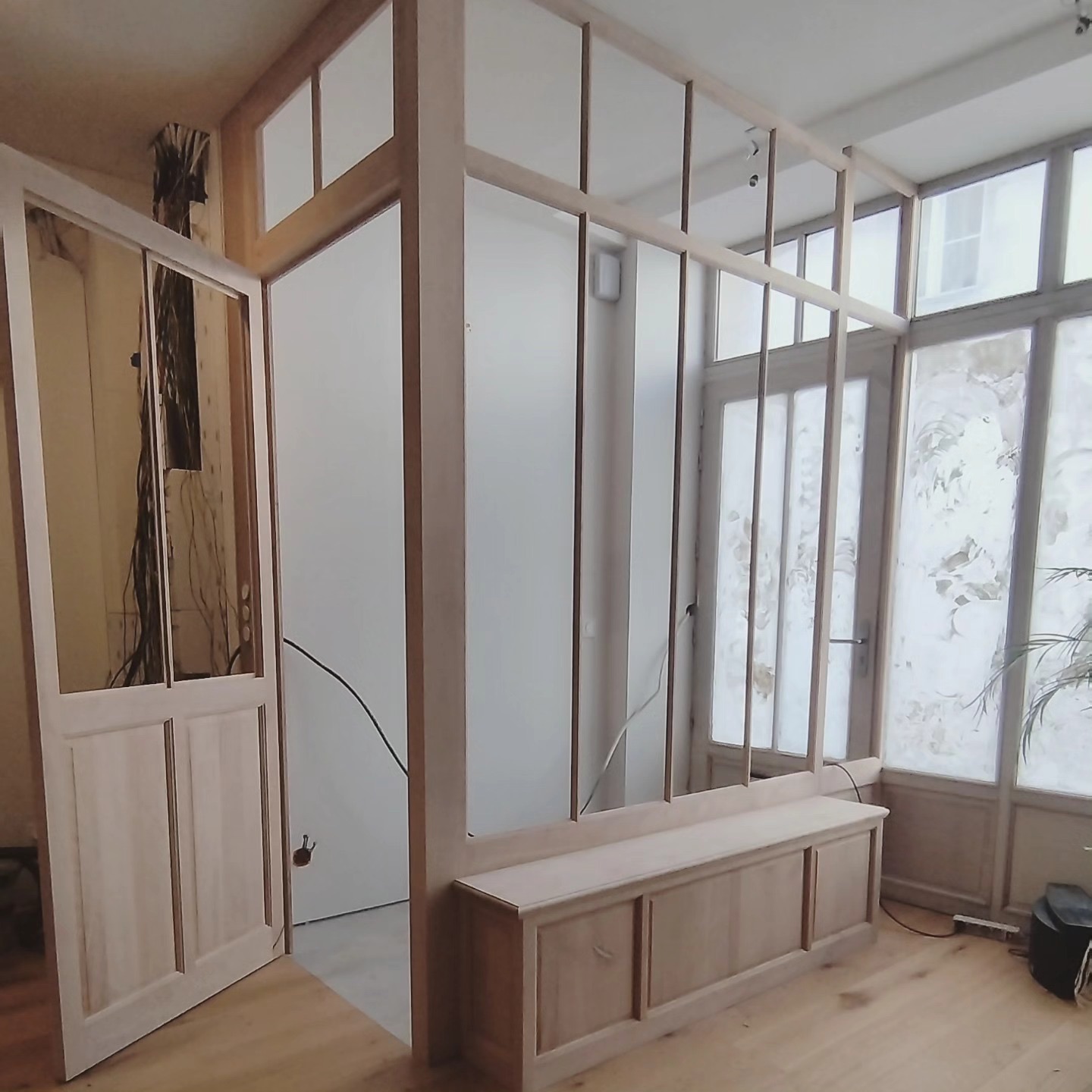 Verrière et cloison en bois avec banc-coffre intégré, en cours de finition