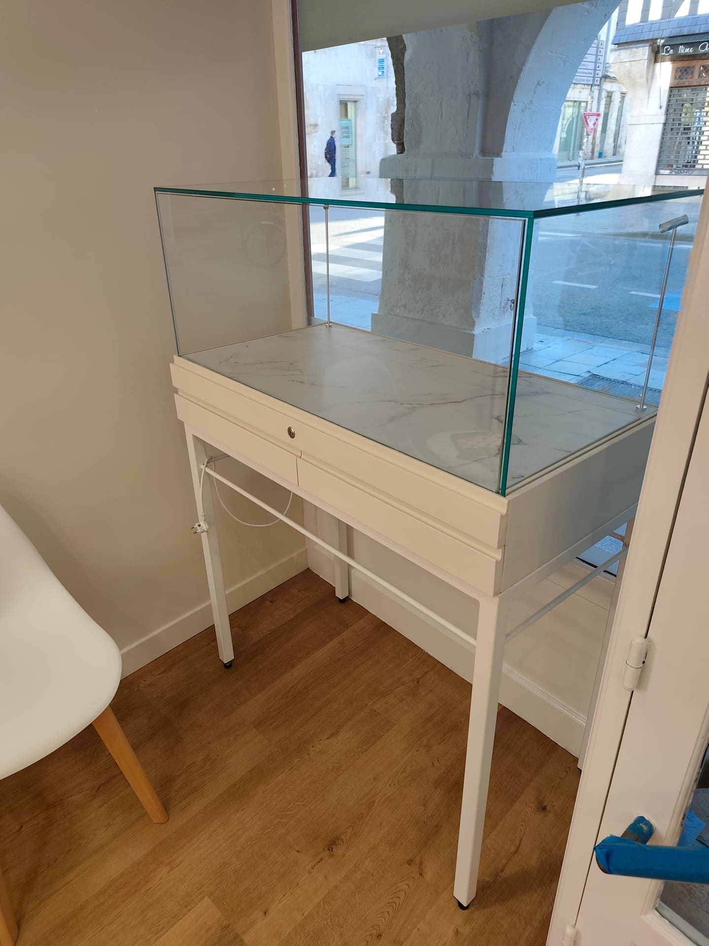 Vitrine d'exposition sur mesure : caisson laqué blanc à tiroirs fermant à clé, plateau effet marbre et cloche en verre sur piètement métal